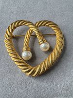 Front view of heart-shaped gold-tone rope brooch with faux pearls