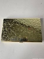 Top view of closed gold plated card holder showing full scroll pattern