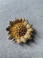 Front view of gold tone sunflower brooch