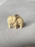 Front view of carved resin elephant pendant showing loop and chain