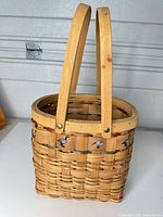 Side view of woven wood basket showing double handles, goose decals, weave pattern