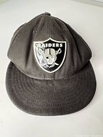 Front view of black Raiders cap with metal crest