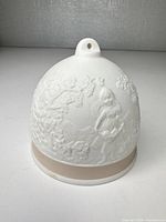 Front view of porcelain bell showing raised girl with basket design