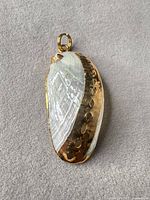 Front view showing iridescent surface, gold-tone bezel, bail