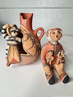 Storyteller figurine seated beside wedding vase with attached dancer