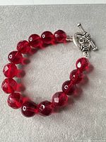Full view of bracelet showing red glass beads and toggle clasp