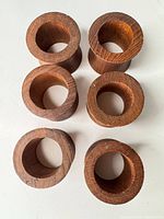Top view of six brown wooden napkin rings showing inner openings and wood grain