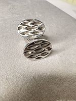Front view of both cufflink faces showing oval shape and recessed diamond pattern