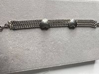 Full view of silver-tone triple chain bracelet with two heart charms