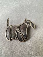 Front view of terrier dog brooch showing design and silver outline