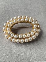 Front view of oval brooch showing two rows of faux pearls and gold-tone setting