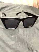 Front view of black cat-eye sunglasses on dark surface