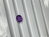 Top view of oval faceted purple amethyst on ridged white surface