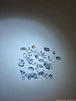 Group of loose multicolored faceted tanzanite stones under spotlight
