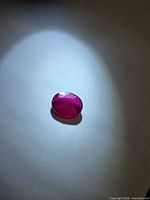Blood-red oval ruby under spotlight