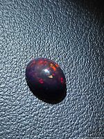 Oval Ethiopian black opal cabochon showing multicoloured fire