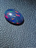 Top view of oval black opal showing multicolour play-of-colour