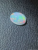 Top view of oval cabochon opal showing multicolour play-of-colour