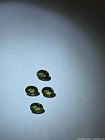 Four oval green sapphires under spotlight on white background