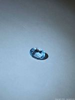 Oval blue faceted gemstone on neutral background