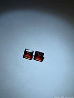 Pair of square red garnets on neutral background