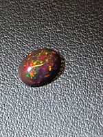 Top view of oval cabochon Ethiopian black opal showing multicolour fire