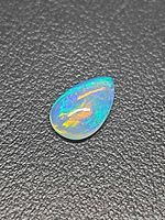 Pear-shape opal showing blue, green and orange play of color on black background