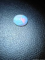 Top view of oval cabochon opal showing red and blue flashes