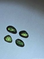 Four loose forest green rose-cut sapphires on white background