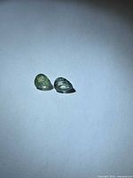 Both pear-cut pastel green sapphires side by side on white background