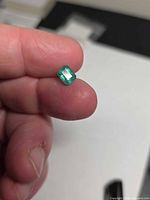 Emerald held between fingers showing table facet and color