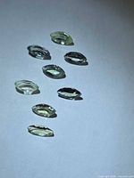 Nine loose marquise-cut pale green tanzanite stones laid out on white background