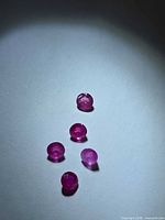 Five rubies arranged on light surface under spot lighting