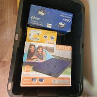 Three boxed items—Intex airbed, Oster waffle maker, Black+Decker chopper—inside tote