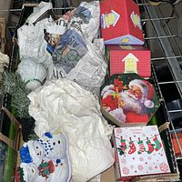 Box of assorted holiday items including Santa tin, hexagonal Santa boxes, snowman ceramic pieces, ornaments
