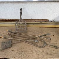 Full view of brass-handled tools and cast iron trivet on work surface