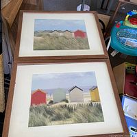 Two coastal beach-hut prints in matching wood frames with white mats