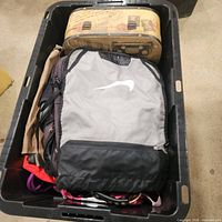 Bin containing gray Nike backpack, map-print box and assorted bags