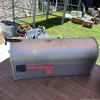 Full side view of aluminum mailbox showing ribbed body and red flag