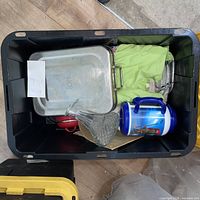 Overview of tote showing stainless pan, green cloth, insulated jug, red saucepan, glass decanter