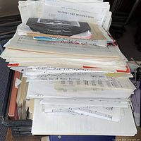 Top-down view of stacked sheet music showing mix of loose sheets and booklets