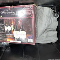 Boxed complete wine making kit next to duffle bag in bin