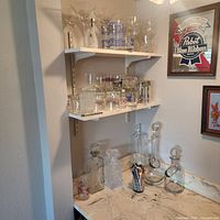 Overall view of shelves and countertop showing decanters, stemware, beer glasses and tumblers