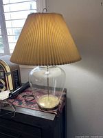 Lamp lit on dresser showing full base and shade