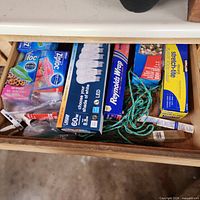 Household consumables drawer showing Ziploc bags, LED bulb pack, plastic wrap, rope and caulk