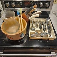 Overview showing knife block, glass pitcher, wooden bowl, flatware tray and loose utensils