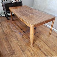 Full view of rectangular wooden dining table with leaf installed