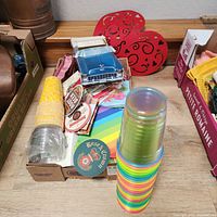 Box with napkins, coasters, plastic cups, red heart decorations and blue model car