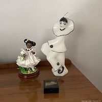 Both figurines on wooden surface with scale cube for size reference