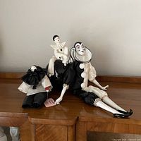 Three Pierrot clown items: trinket box and two dolls displayed on wooden surface